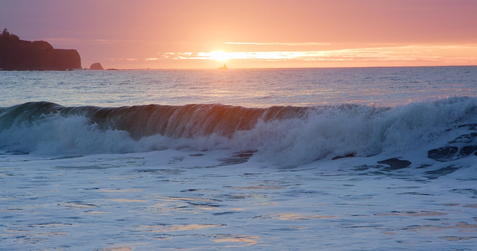 Waves crashing with the sunset above