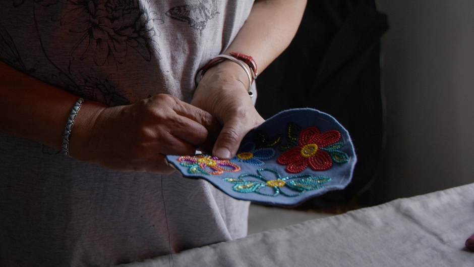 An elder shows her art for the viewer